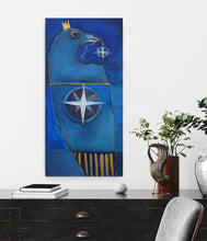Load image into Gallery viewer, A vertical oil on canvas painting featuring a stylized blue raven with a gold crown and a white compass-like star motif, displayed on a white wall above a dark wooden console table with books, a plant, and a chair.